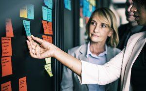 Businesspeople planning tasks with sticky notes