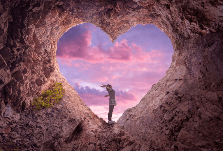 Woman in the center of a heart cave opening